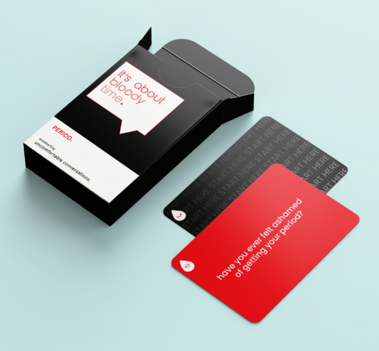 A deck of cards called "it's about bloody time." with two cards next to the pack, one black and one red, the red one says "have you ever felt ashamed of getting your period?" 